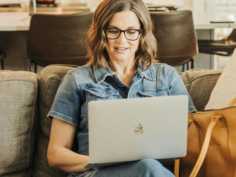 Frau mit Laptop sitzt im Wohnzimmer